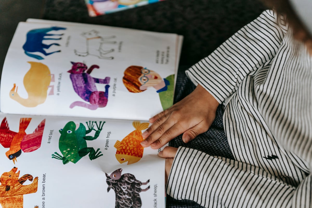 Child watching bright pictures with animals in book